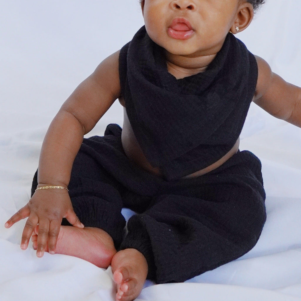 Baby sitting on a white sheet with a plain background