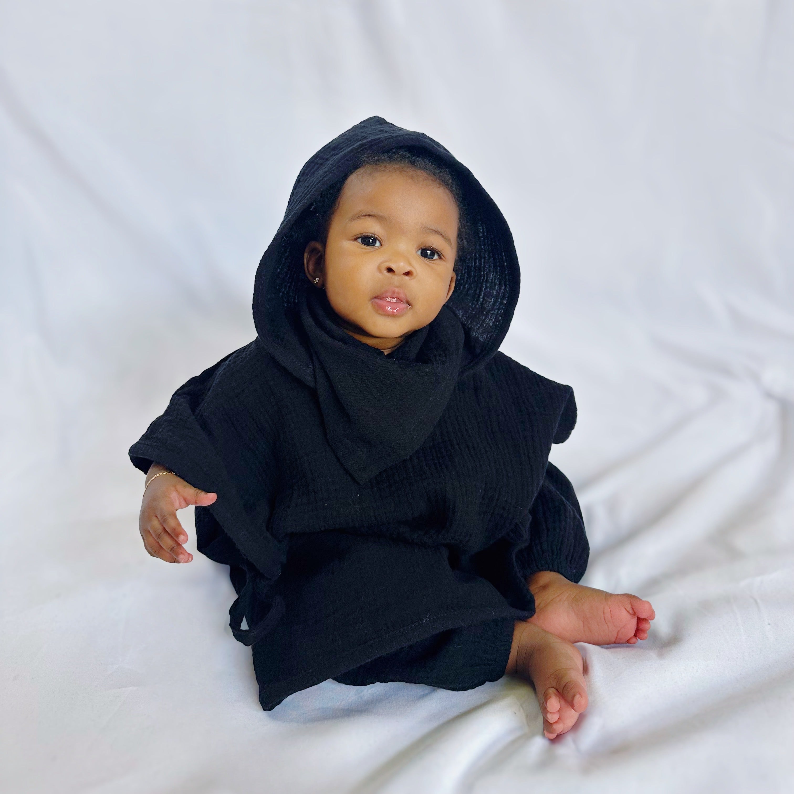 Baby wearing a black hooded outfit on a white background